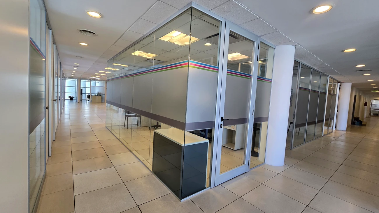 Corredor de oficinas con frente vidriado y puerta de doble hoja de aluminio y vidrio