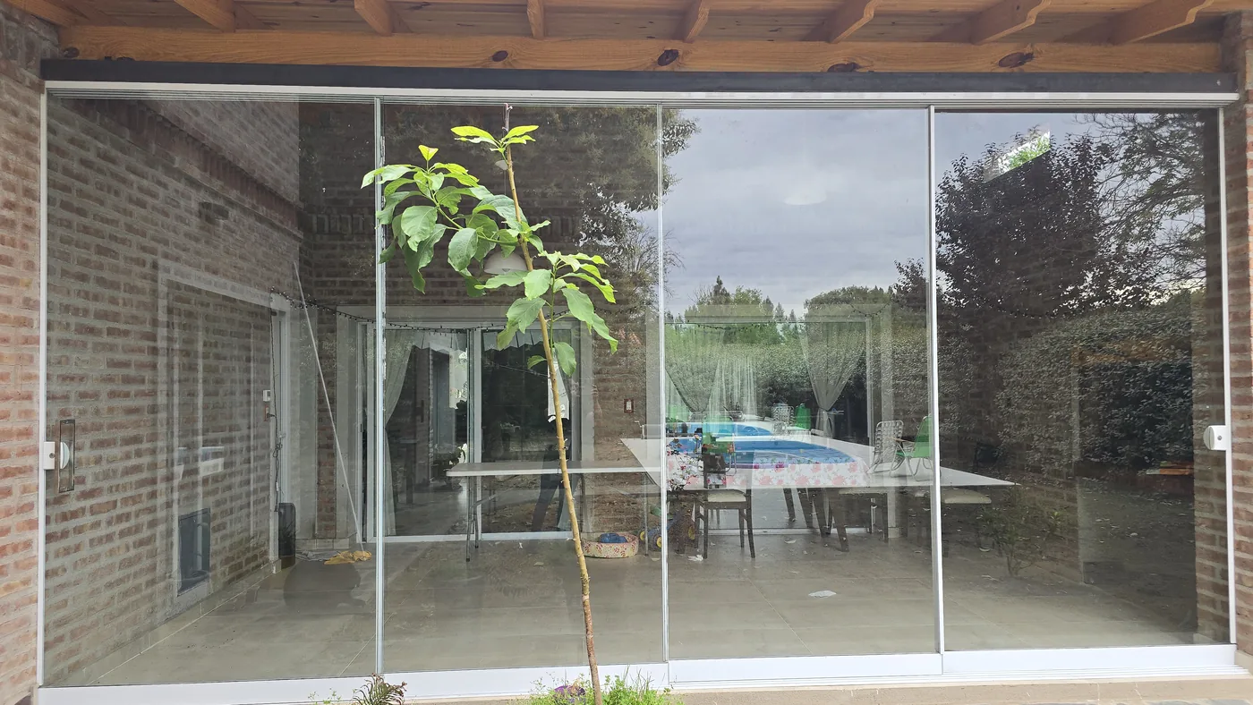 Galería cerrada con sistema minimalista de vidrio y perfilería de aluminio natural - obra de JN Aluminio en Neuquén