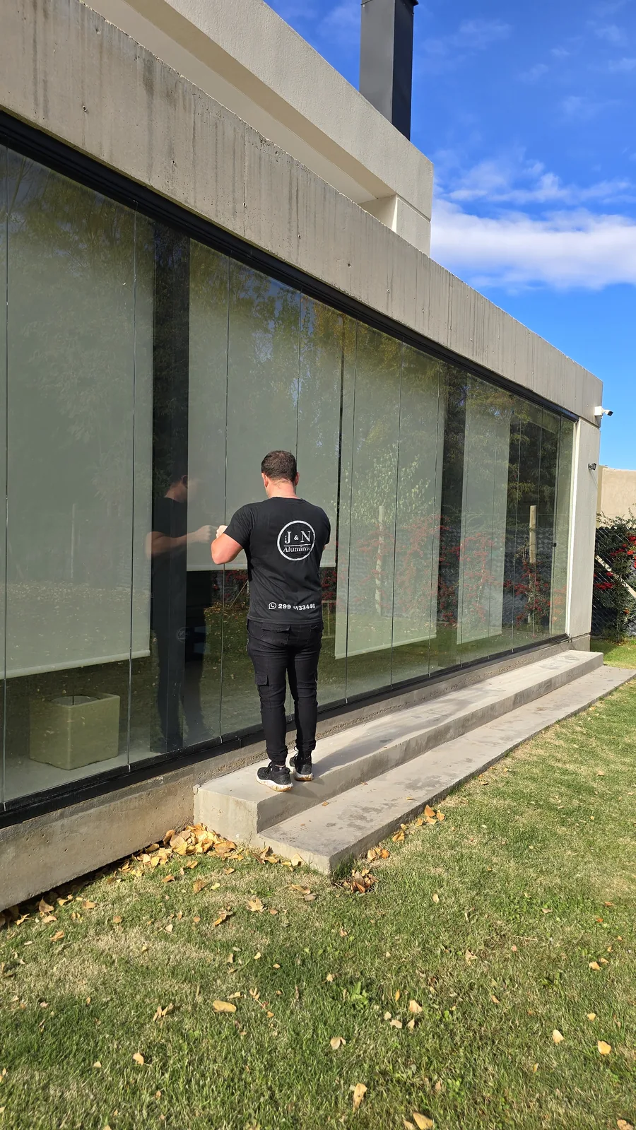 Instalador de JN Aluminio accionando un paño de cortina de cristal en Neuquén