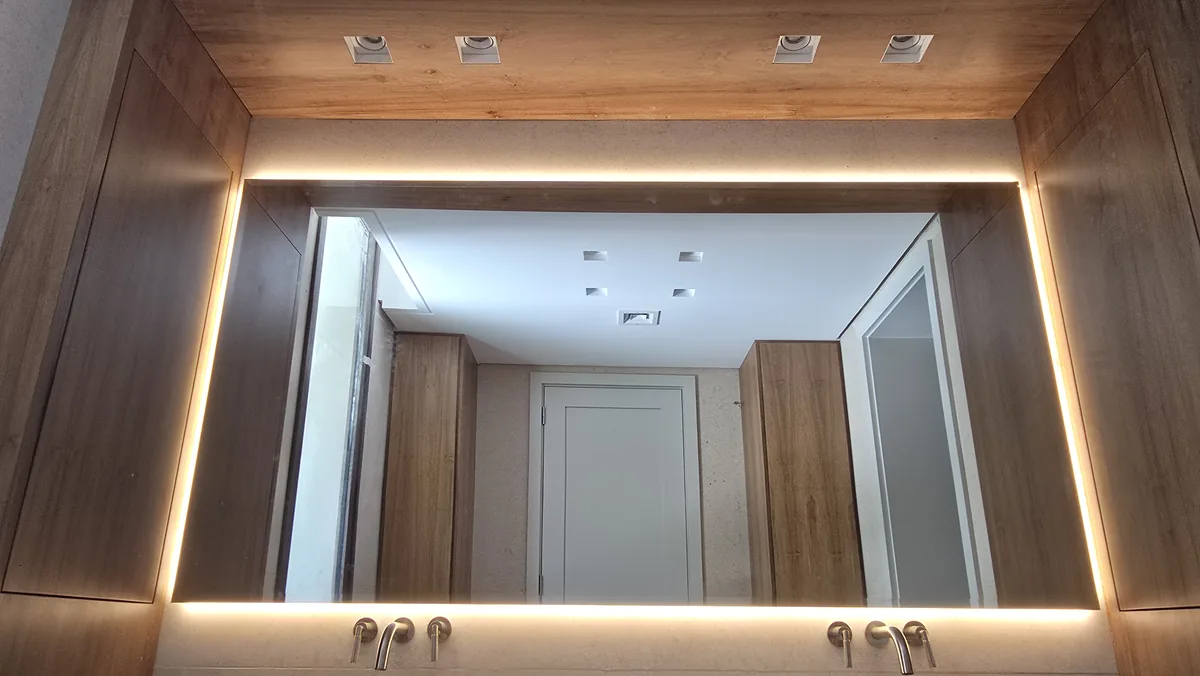 Espejo LED retroiluminado con marco de madera en baño principal - JN Aluminio Neuquén