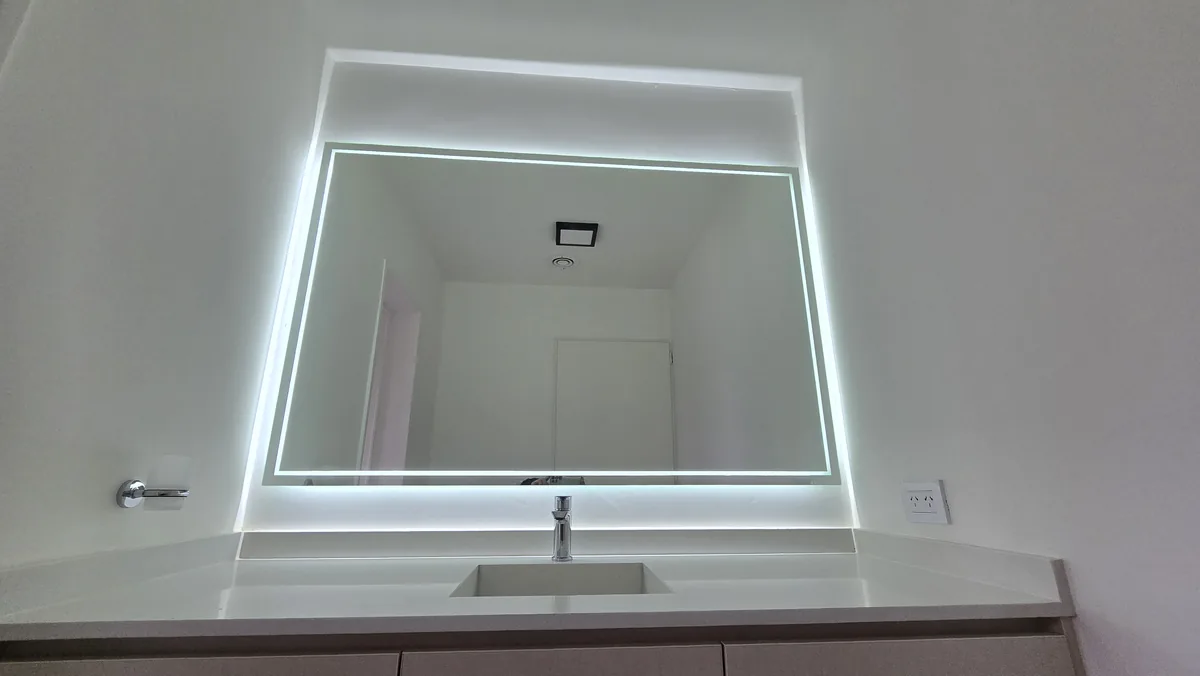 Espejo LED con luz perimetral sobre vanitory de un baño en Neuquén - instalación de J&N Aluminio
