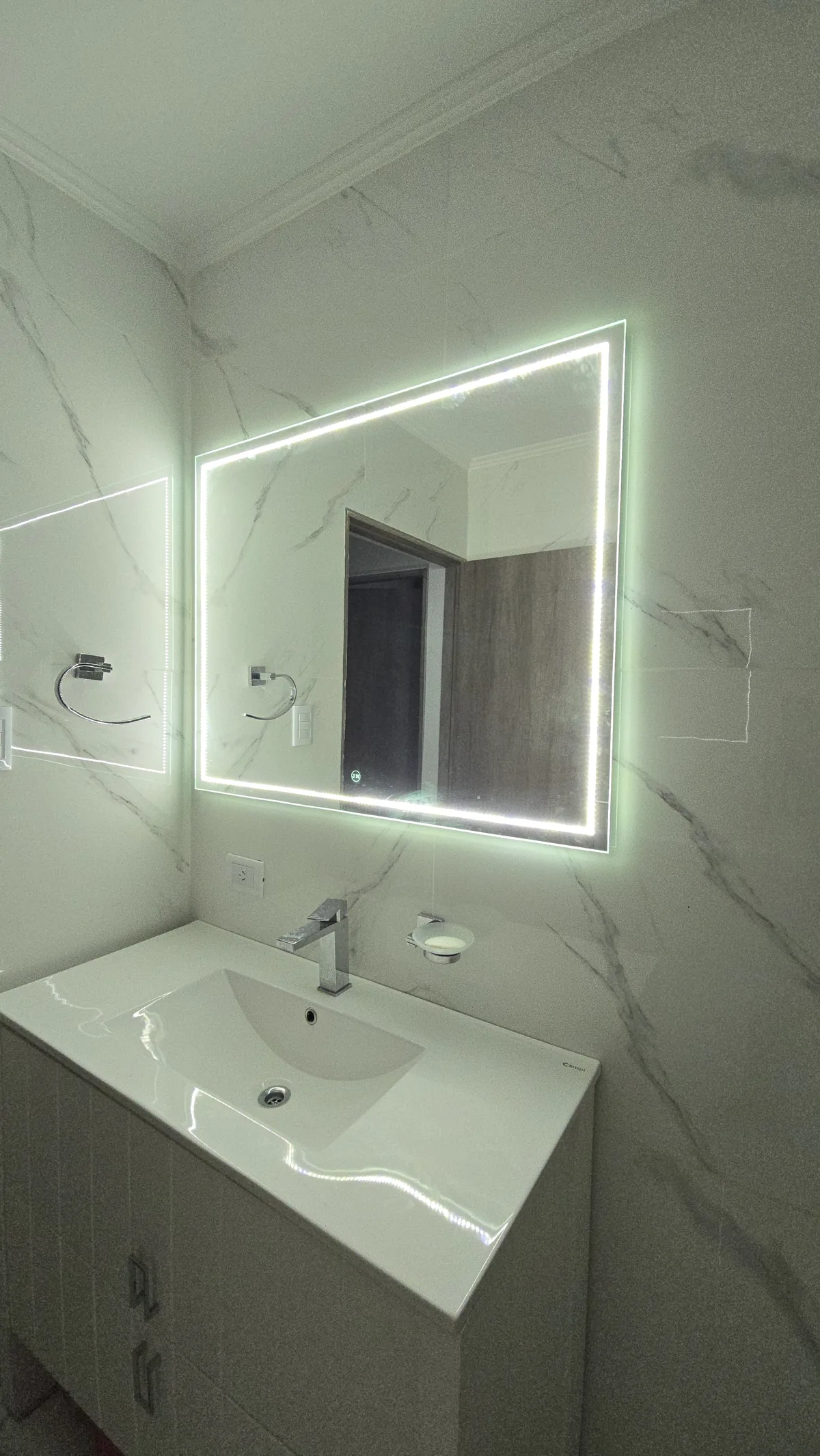 Espejo LED rectangular con luz perimetral sobre mesada de mármol blanco - instalación de J&N Aluminio en Neuquén