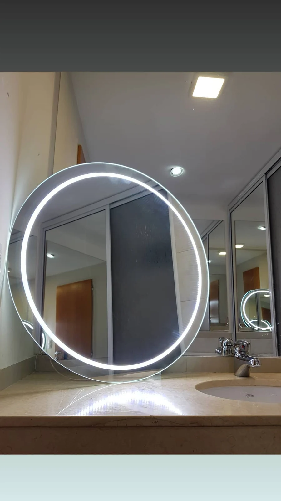 Espejo LED redondo retroiluminado en baño claro - instalación de J&N Aluminio en Neuquén