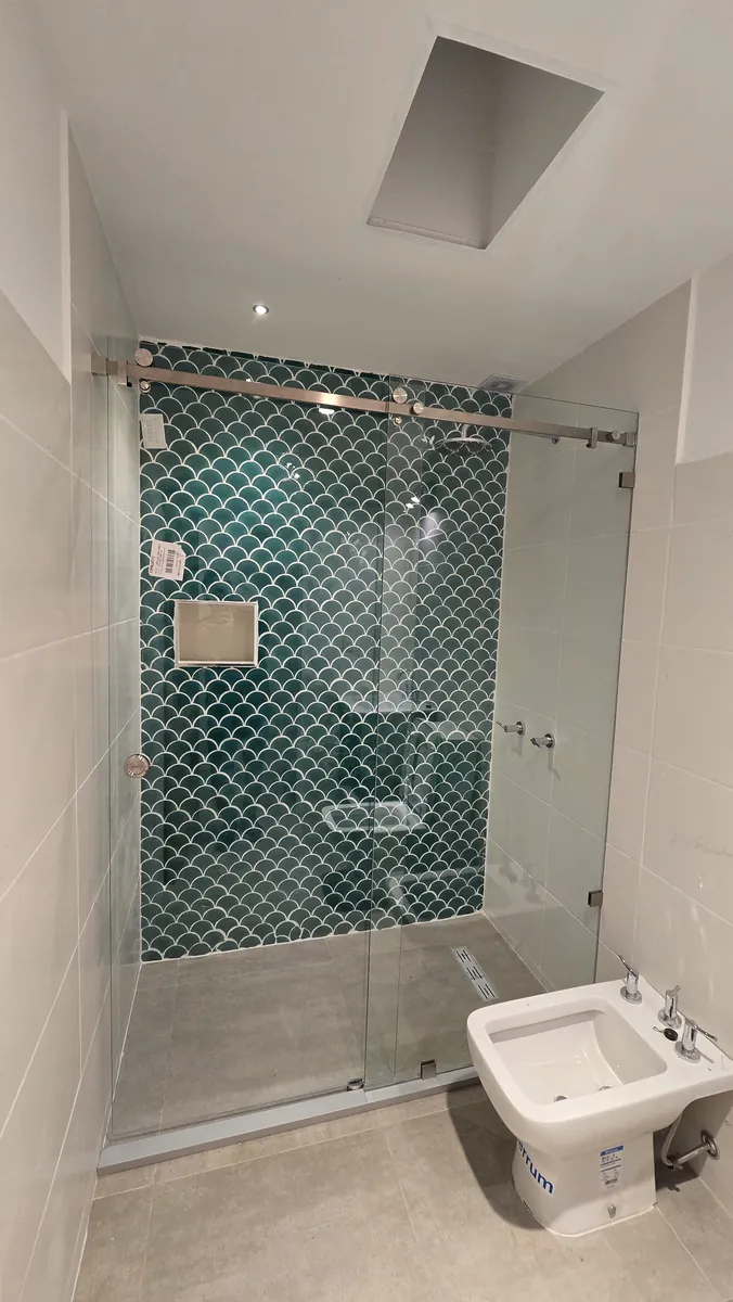 Mampara corrediza con paño fijo, herraje Steel de acero inoxidable pulido y vidrio templado Blindex transparente - obra de J&N Aluminio en Neuquén