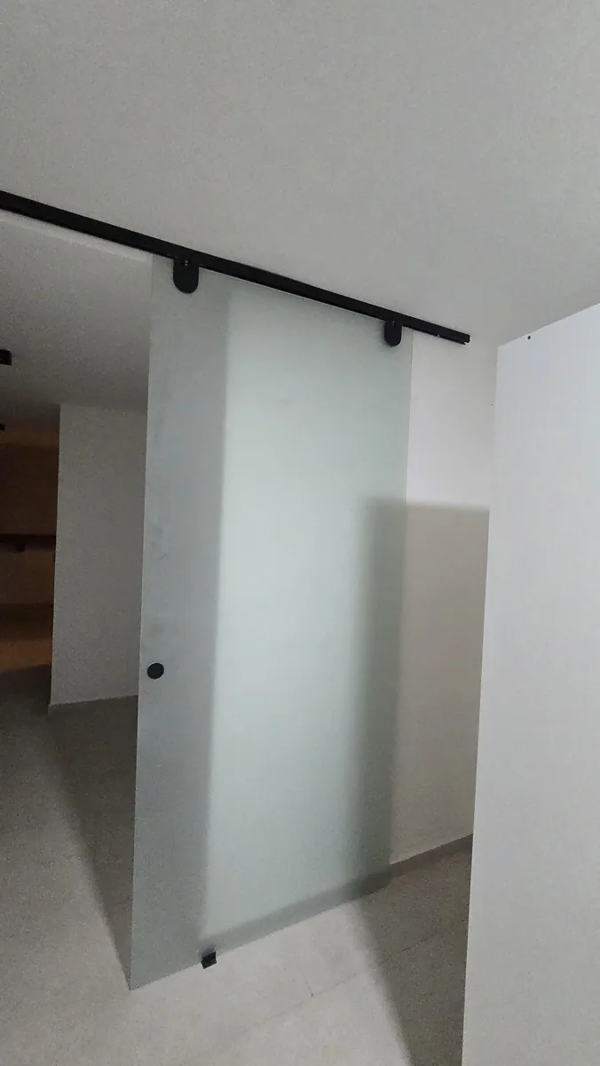 Mampara corrediza colgante tipo granero con herraje negro y vidrio templado Blindex esmerilado - obra de J&N Aluminio en Neuquén