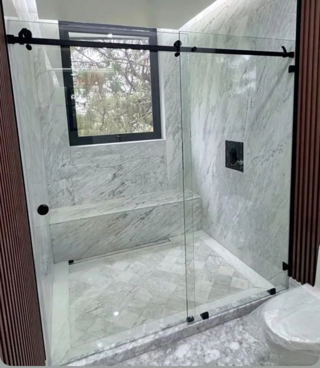 Mampara corrediza con herraje Steel de acero inoxidable negro y vidrio templado - obra de J&N Aluminio en Neuquén