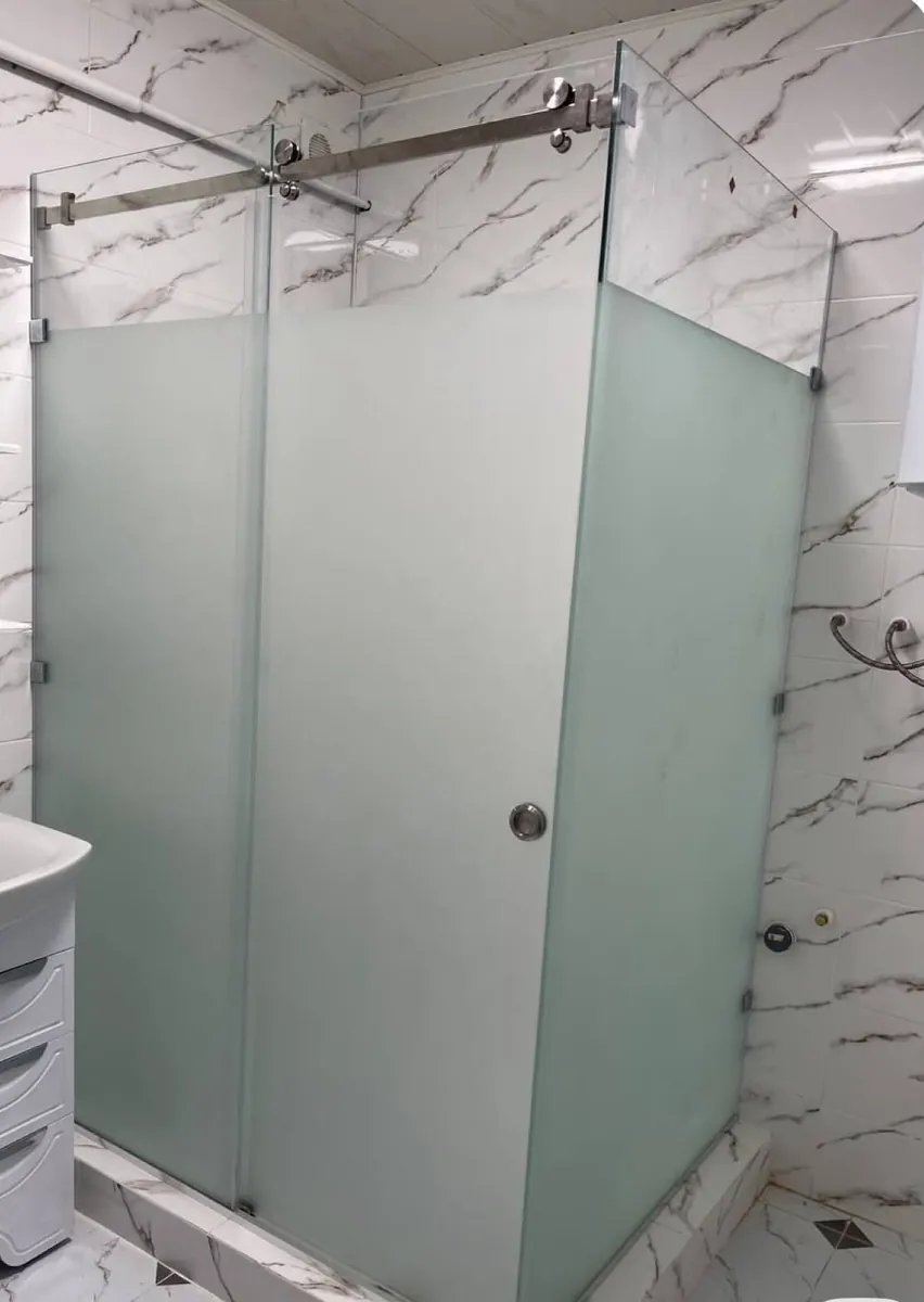 Box de ducha esquinero con paños fijos lateral y frontal, herraje Steel de acero inoxidable satinado y vidrio templado con ploteo esmerilado gris - obra de J&N Aluminio en Neuquén