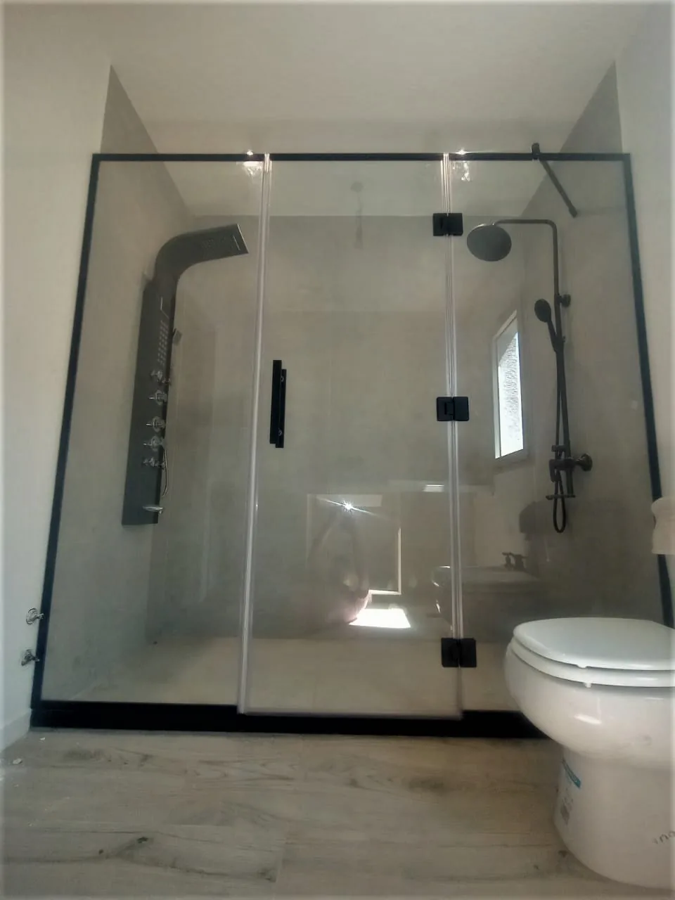 Mampara corrediza de vidrio templado con perfilería negra y barral superior - instalación de J&N Aluminio en Neuquén
