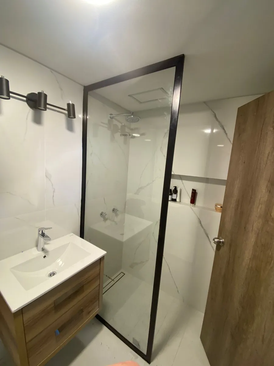 Mampara de paño fijo con perfil perimetral en U de aluminio negro y vidrio laminado Blindex 5+5 - obra de J&N Aluminio en Neuquén