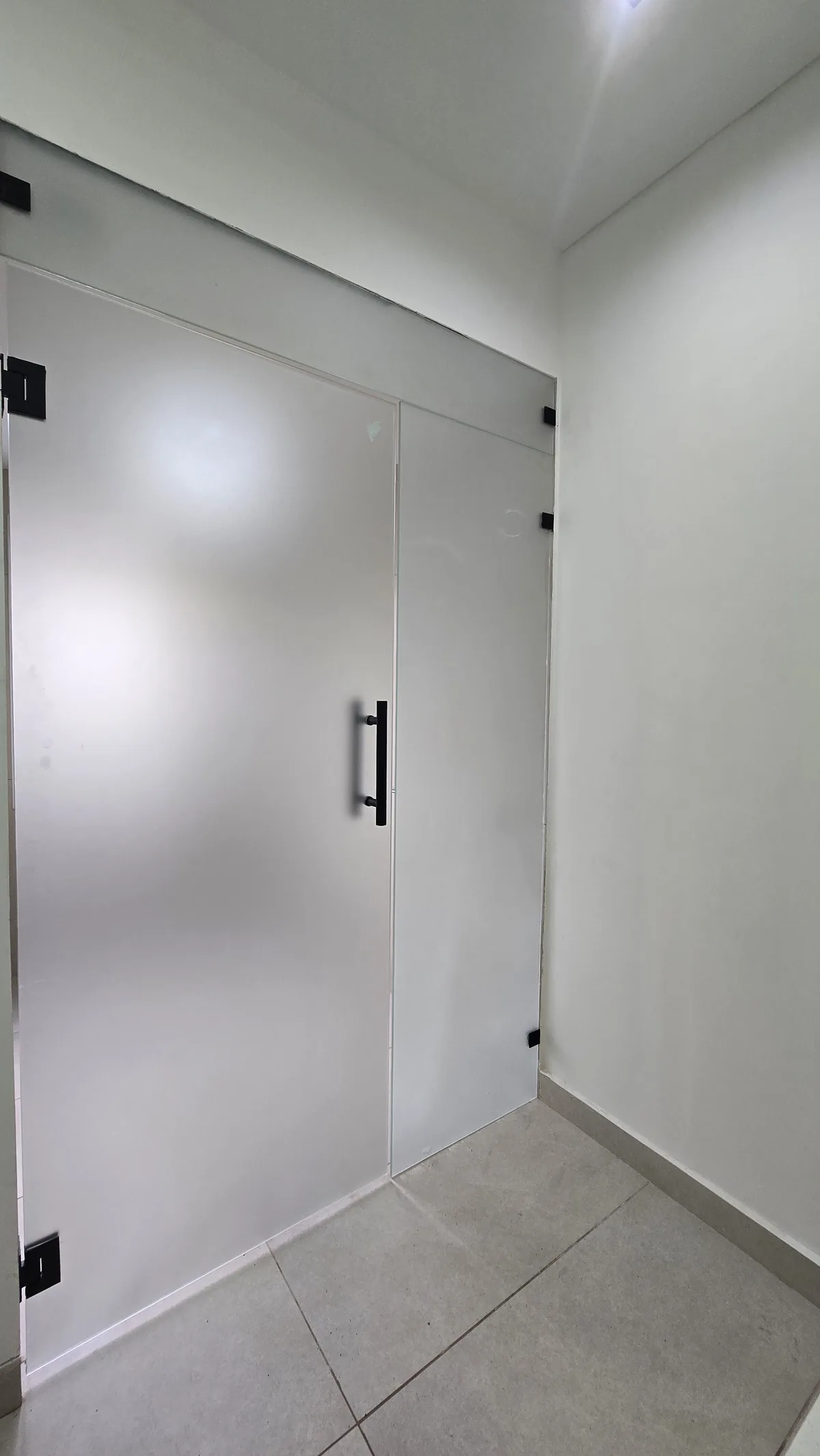 Mampara rebatible de vidrio templado satinado con herrajes negros y manija barral - obra de JN Aluminio en Neuquén