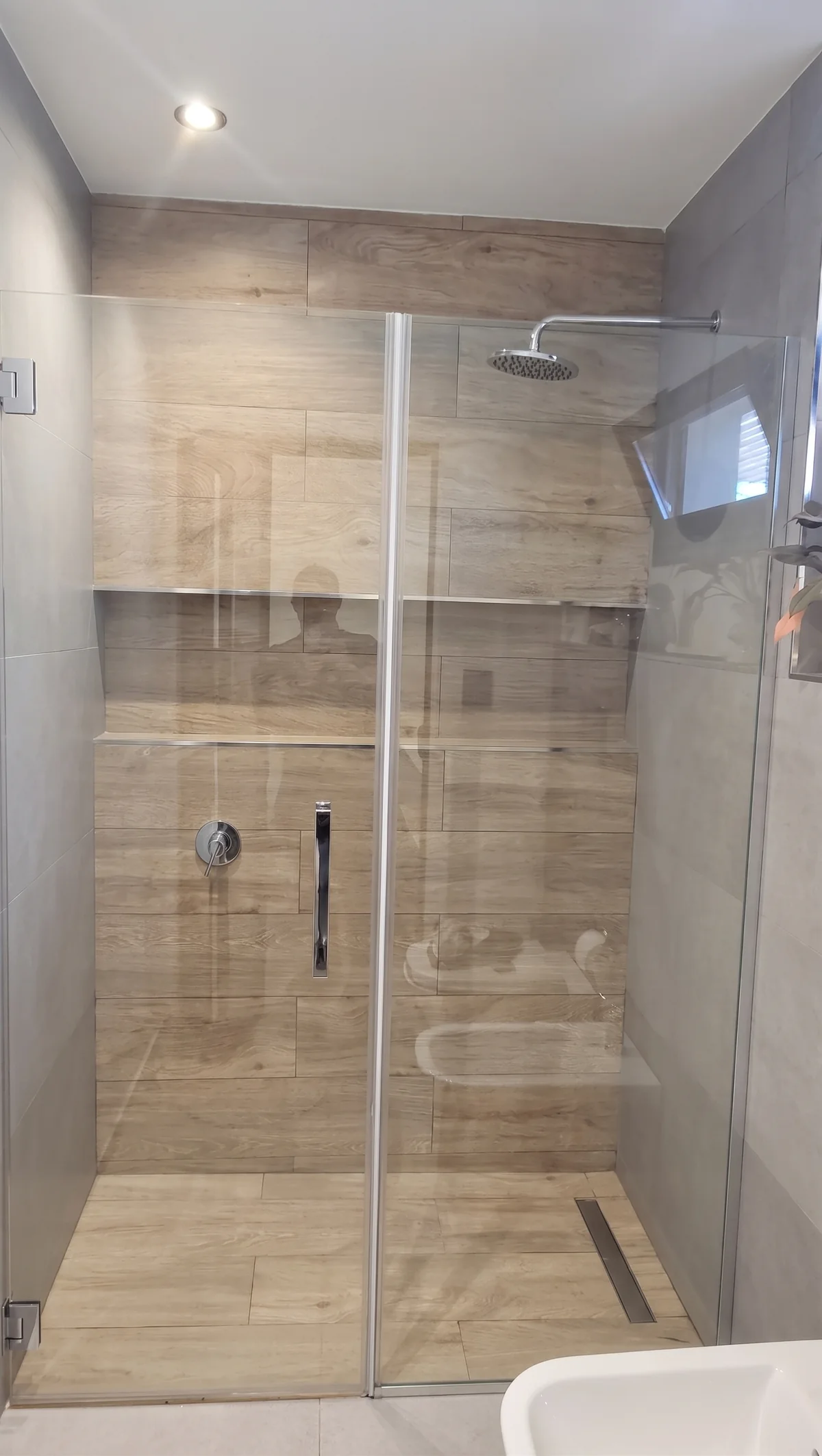 Mampara rebatible con paño fijo y manija de acero en baño revestido en madera - JN Aluminio Neuquén