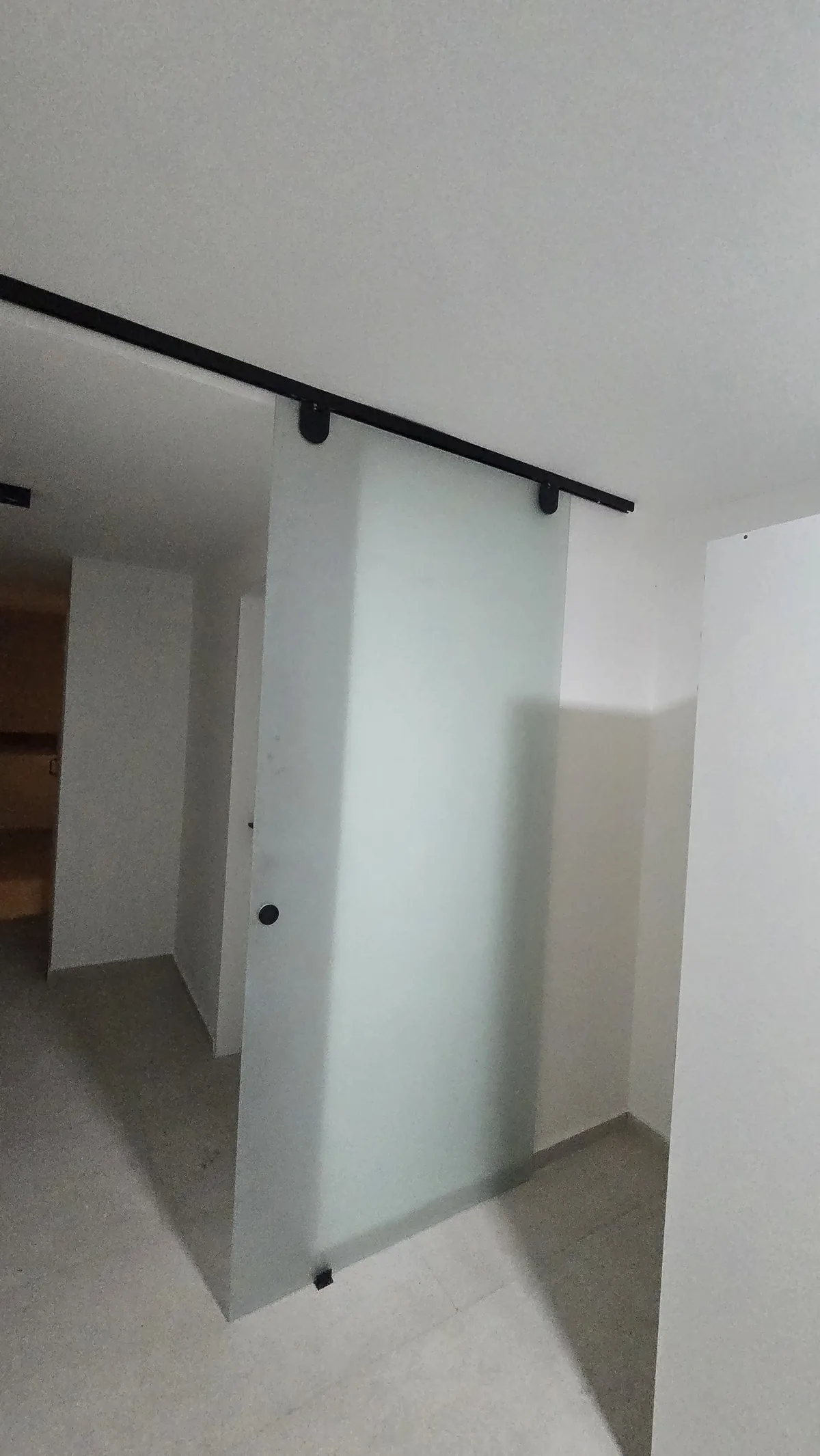 Puerta granero de vidrio templado satinado sobre riel negro a la vista - obra de JN Aluminio en Neuquén
