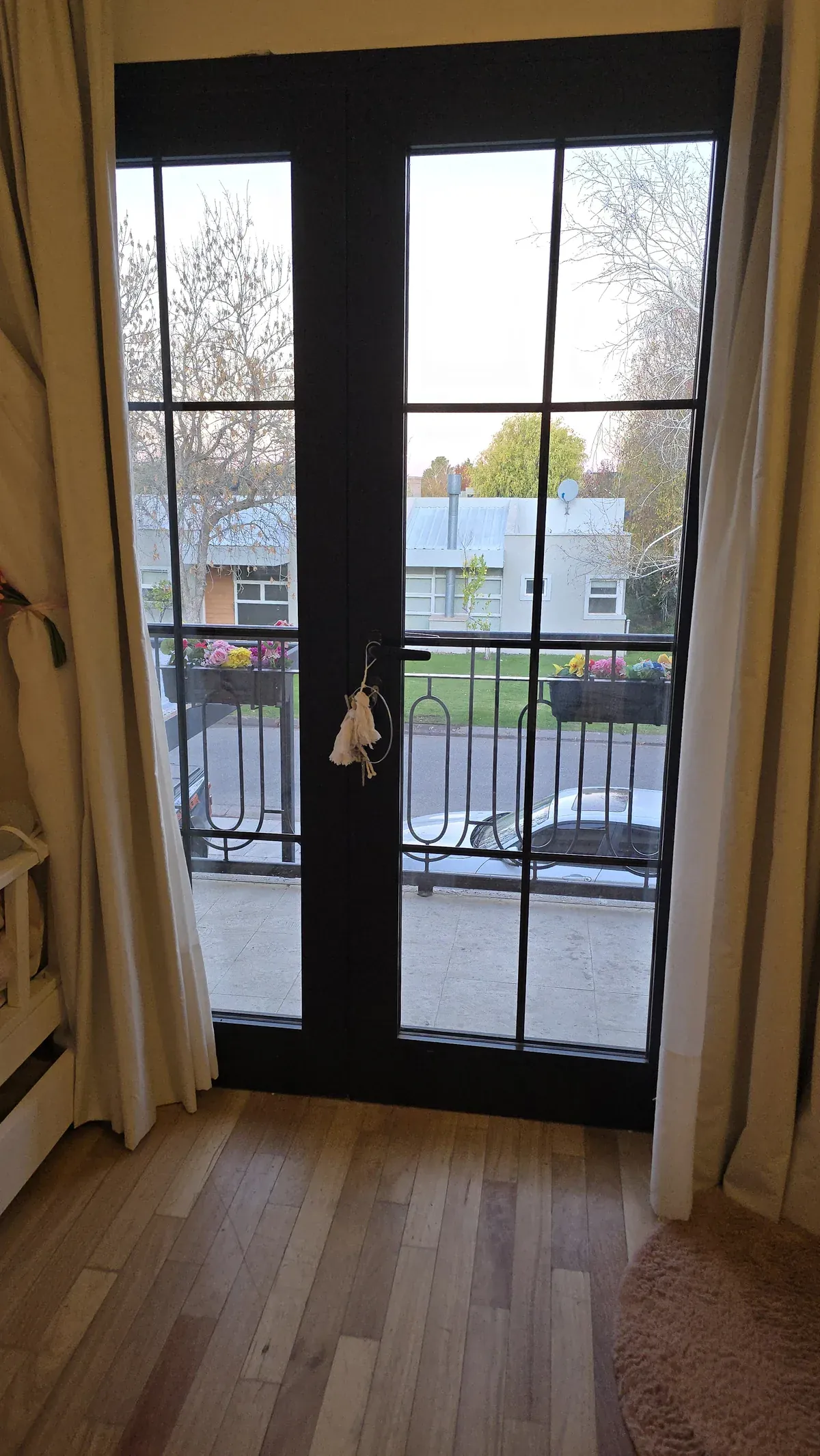 Puerta ventana doble de aluminio negro línea Premium hacia el balcón, con DVH y barrotillos internos que simulan vidrio repartido - obra de J&N Aluminio en Neuquén