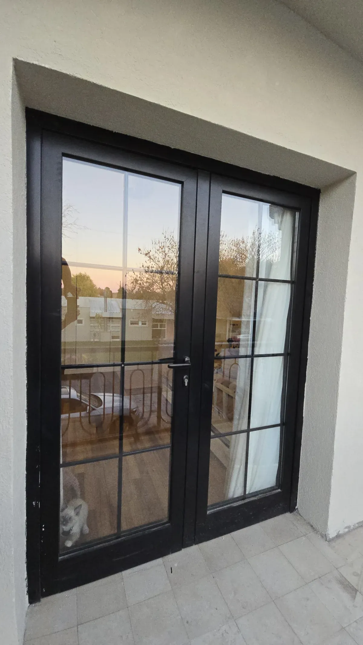 Puerta ventana doble de aluminio negro línea Premium de alta prestación, con DVH y barrotillos internos que simulan vidrio repartido, hacia el balcón - obra de J&N Aluminio en Neuquén