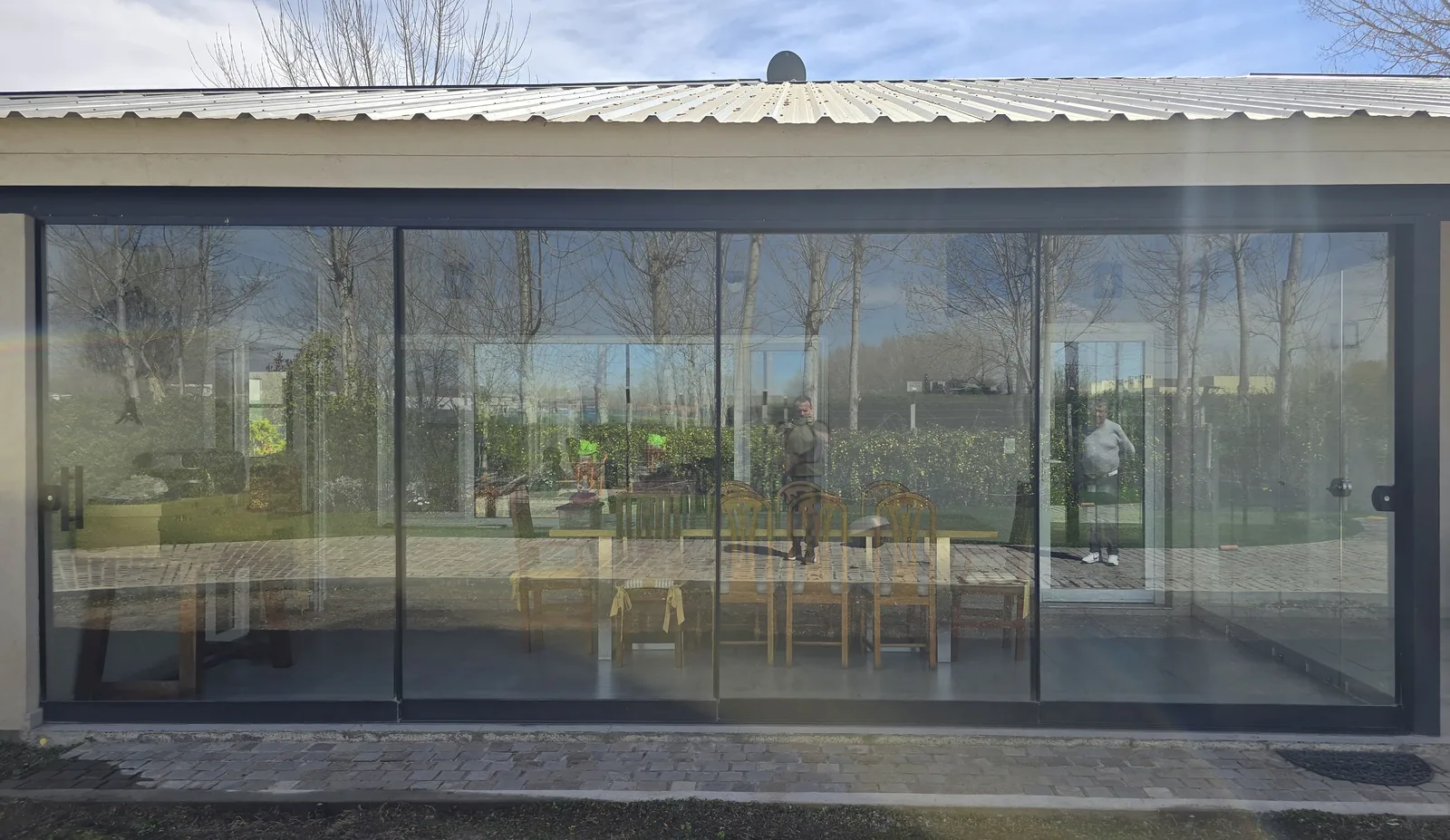 Frente completo del cerramiento deslizante: cuatro paños de vidrio templado de 10 mm con perfilería negra mínima, 6,5 metros de ancho por 2,70 de alto - obra de J&N Aluminio en Los Canales, Plottier
