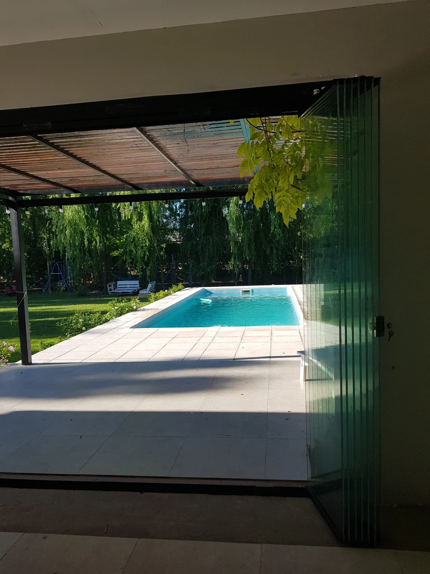 Cortina de cristal completamente abierta y plegada hacia el jardín - obra de JN Aluminio en Neuquén