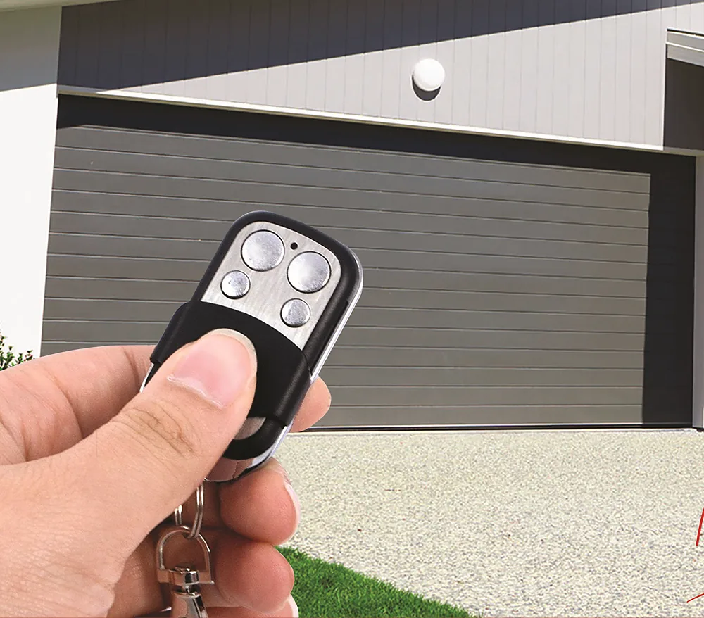Portón automático enrollable Modelo 125 en una casa moderna, con el control remoto en la mano - J&N Aluminio Neuquén