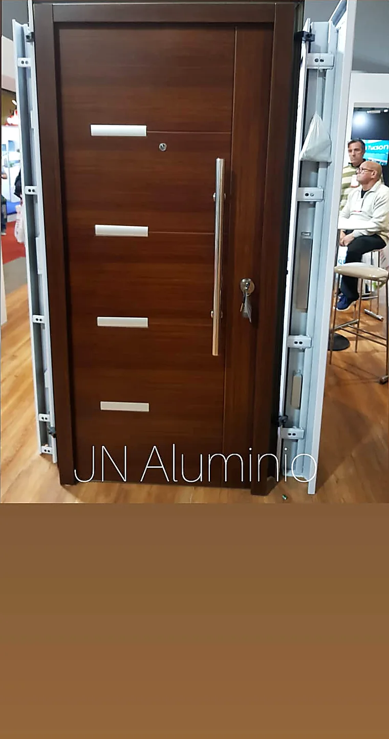 Puerta de seguridad multianclaje símil madera con apliques de inox en el showroom de J&N Aluminio, Neuquén