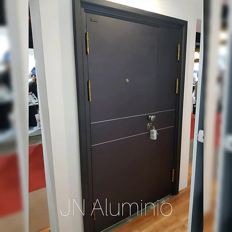 Puerta de seguridad multianclaje símil madera oscura lisa en el showroom de J&N Aluminio, Neuquén