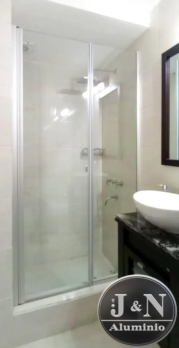 Mampara batiente de vidrio templado en baño moderno con mesada de mármol - JN Aluminio Neuquén