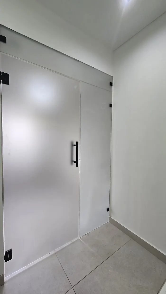 Mampara rebatible de vidrio templado satinado con herrajes negros - obra de JN Aluminio en Neuquén