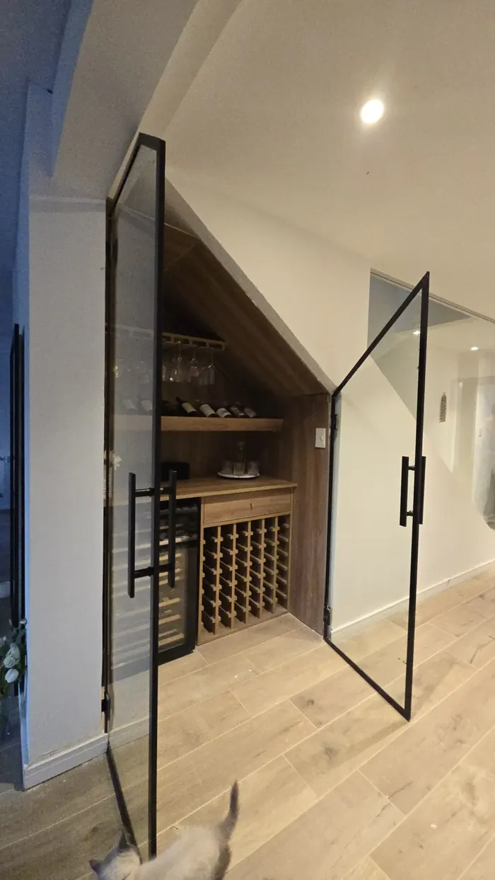 Cava de vino bajo escalera cerrada con puerta de vidrio templado y perfilería negra - obra de JN Aluminio en Neuquén