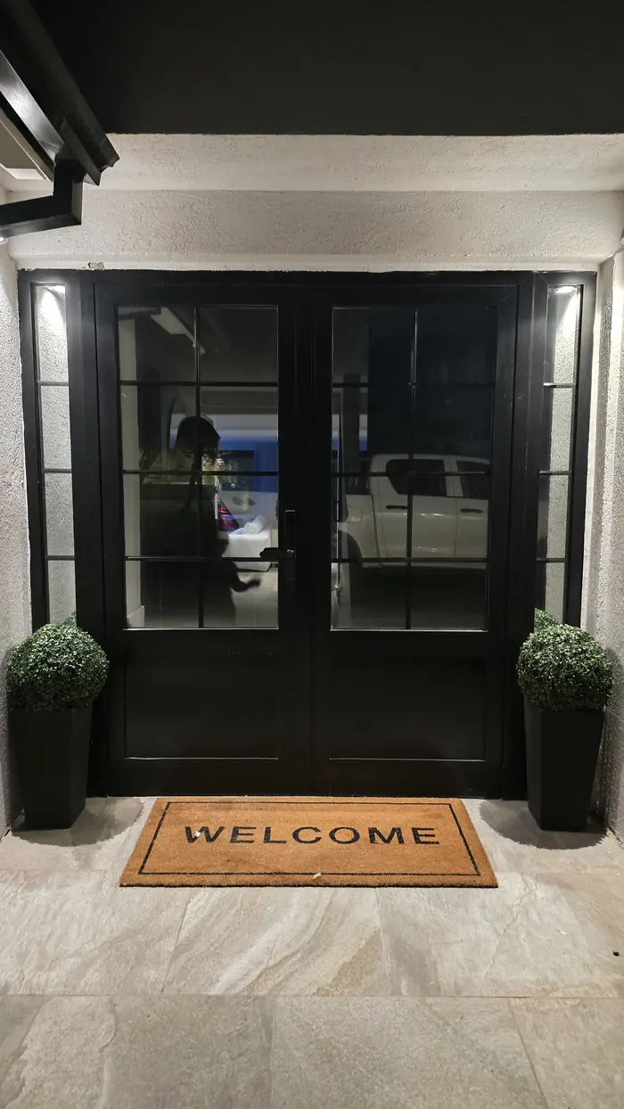 Puerta doble de entrada de vivienda en aluminio negro línea Premium, con DVH y barrotillos internos que simulan vidrio repartido y paños laterales - JN Aluminio Neuquén