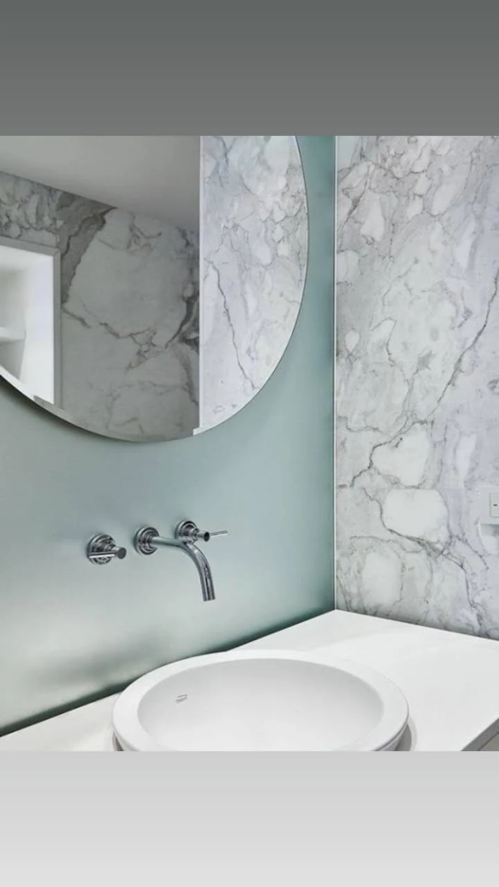 Vidrio y espejo a medida en baño revestido en mármol - obra de J&N Aluminio en Neuquén